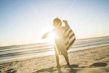 Boy with a towel standing on the beach at sunset - SDAHF00362