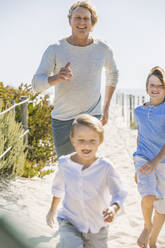 Vater hat Spaß mit seinen Söhnen am Strand, rennt und springt im Sand - SDAHF00368