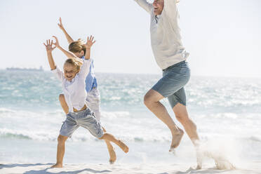 Father having fun with his sons on the beach, running and jumping in the sand - SDAHF00369