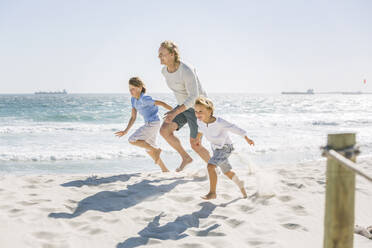 Father having fun with his sons on the beach, running and jumping in the sand - SDAHF00370