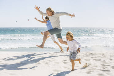 Father having fun with his sons on the beach, running and jumping in the sand - SDAHF00371