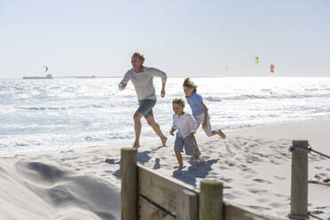 Vater hat Spaß mit seinen Söhnen am Strand, rennt und springt im Sand - SDAHF00372