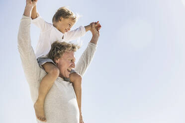 Father having fun with his son on the beach, carrying him piggyback - SDAHF00378