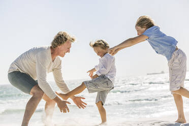 Vater hat Spaß mit seinen Söhnen am Strand, rennt und springt im Sand - SDAHF00379