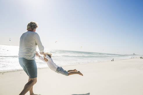 Father having fun with his son on the beach, spinning him around - SDAHF00382