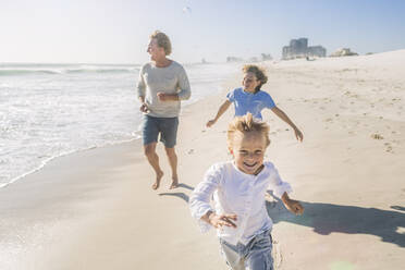 Father having fun with his sons on the beach, running and jumping in the sand - SDAHF00385