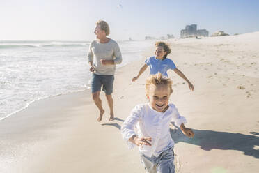 Vater hat Spaß mit seinen Söhnen am Strand, rennt und springt im Sand - SDAHF00385