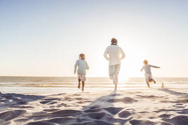 Father having fun with his sons on the beach, running in the sand - SDAHF00406