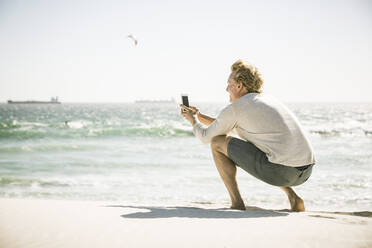 Mann, der ein Smartphone-Foto am Strand macht - SDAHF00412