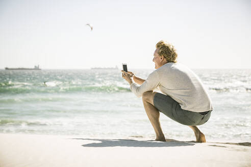 Man taking a smartphone picture on the beach - SDAHF00412