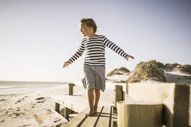 Boy balancing on boardwalk at the beach - SDAHF00416