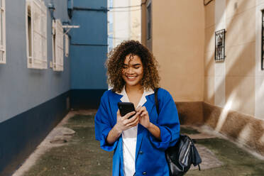 Portrait of smiling woman writing a mobile message in the city - TCEF00176