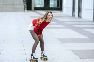 Blond woman rollerskating on a square - KIJF02891