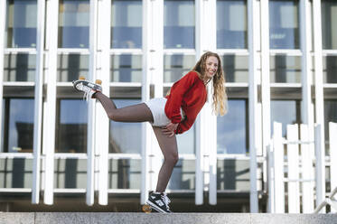 Blond woman balancing with roller skates - KIJF02892