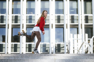 Blond woman balancing with roller skates - KIJF02893