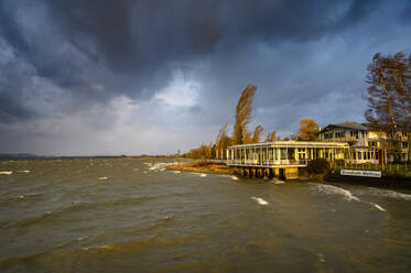 Deutschland, Baden-Württemberg, Radolfzell am Bodensee, Gewitterwolken über Cafe am Bodenseeufer - ELF02129