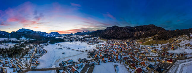 Germany, Bavaria, Reit im Winkl, Helicopter view of snow-covered mountain village at dawn - AMF07834