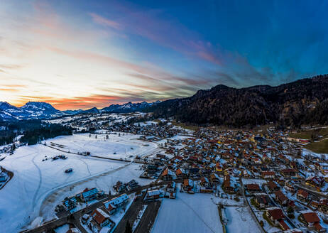 Deutschland, Bayern, Reit im Winkl, Blick aus dem Hubschrauber auf ein schneebedecktes Bergdorf in der Morgendämmerung - AMF07835