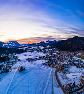 Deutschland, Bayern, Reit im Winkl, Blick aus dem Hubschrauber auf ein schneebedecktes Bergdorf in der Morgendämmerung - AMF07836