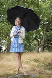 Lächelnde junge Frau mit Regenschirm - JOHF08279