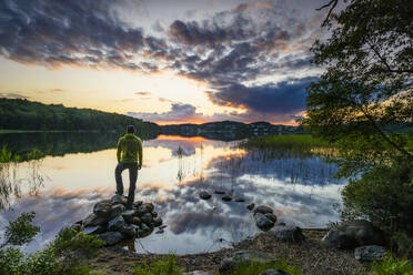 Mann stehend am See bei Sonnenuntergang - JOHF08290