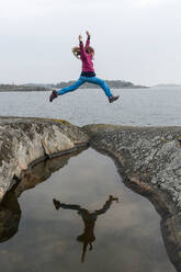 Mädchen springt am Seeufer - JOHF08312