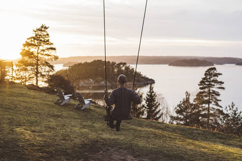 Man swinging on swing at seaside - JOHF08400