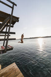 Girl jumping into sea - JOHF08526