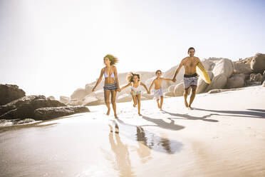 Glückliche Familie beim Laufen am Strand - SDAHF00460