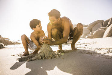 Vater und Sohn bauen gemeinsam eine Sandburg am Strand - SDAHF00471