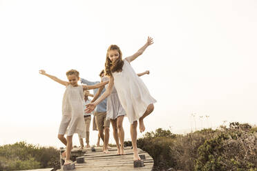 Large family enjoying the sunset balancing on a boardwalk - SDAHF00480
