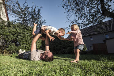 Vater spielt mit seinen beiden Kindern im Garten - WFF00259