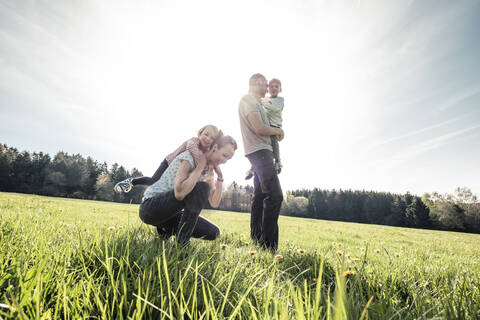 Glückliche Familie mit zwei Kindern auf einer Wiese im Frühling, lizenzfreies Stockfoto