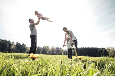 Glückliche Familie mit zwei Kindern auf einer Wiese im Frühling - WFF00284