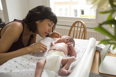 Loving mother watching newborn baby son laying on changing table - HOXF04930