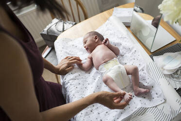 Mother changing diaper of newborn baby son on changing table - HOXF04936