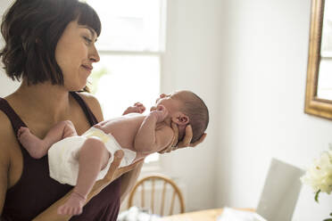 Mother cradling newborn baby son in diaper - HOXF04941