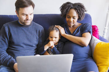 Schwangere Familie mit Laptop auf dem Sofa - HOXF04963