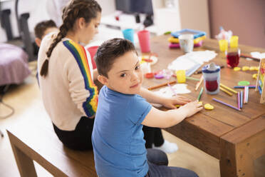Porträt niedlichen Jungen mit Down-Syndrom Färbung am Tisch mit Schwester - HOXF04993