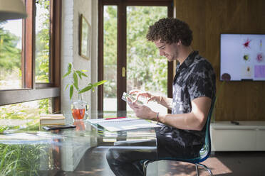 Junger Mann mit digitalem Tablet bei der Arbeit im Heimbüro - HOXF04998