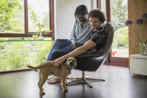 Glückliches junges Paar mit Hund im Heimbüro, lizenzfreies Stockfoto