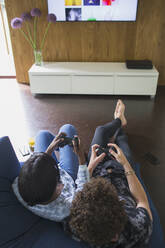 Young couple playing video game in living room - HOXF05015