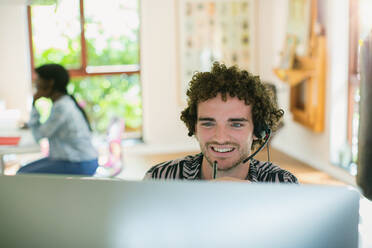 Young man with headset working at computer in home office - HOXF05025