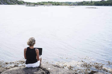 Frau benutzt Laptop auf See - JOHF08807