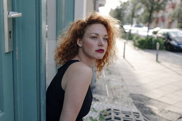 Porträt einer rothaarigen Frau, die vor einem Café steht und zur Seite schaut - OGF00123