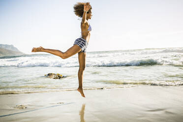 Happy young woman jumping on the beach - SDAHF00503