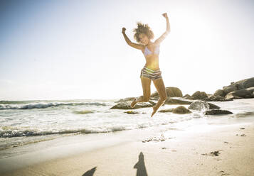 Happy young woman jumping on the beach - SDAHF00507