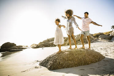 Glückliche Familie balanciert auf einem Felsen am Strand - SDAHF00510