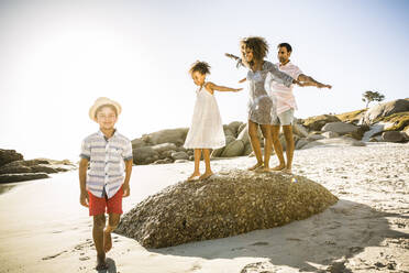Glückliche Familie balanciert auf einem Felsen am Strand - SDAHF00511