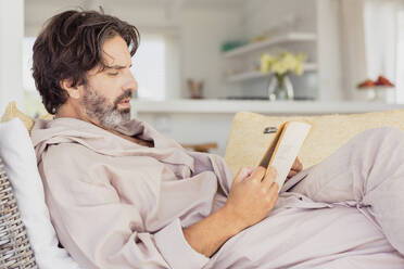 Relaxed man in bathrobe reading a book - SDAHF00523